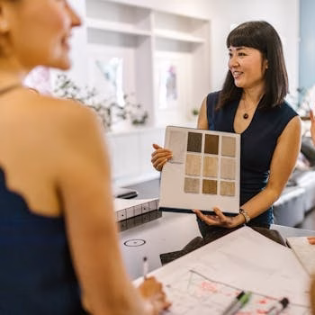 Interior designer presenting color swatches to clients in a modern workspace, fostering a creative atmosphere.